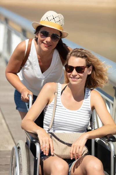 Φίλη Και Ανάπηρη Γυναίκα Στο Αναπηρικό Καροτσάκι Στην Παραλία — Φωτογραφία Αρχείου