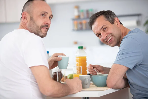 キッチンで朝食を食べる幸せなゲイカップル — ストック写真