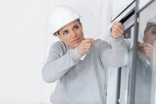 Junge Arbeiterin Entfernt Schutzkleber Fenstern — Stockfoto