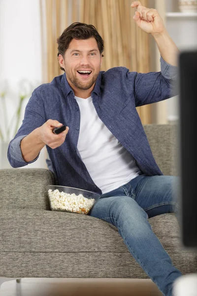 Szczęśliwy Człowiek Oglądając Telewizję Jedząc Popcorn — Zdjęcie stockowe