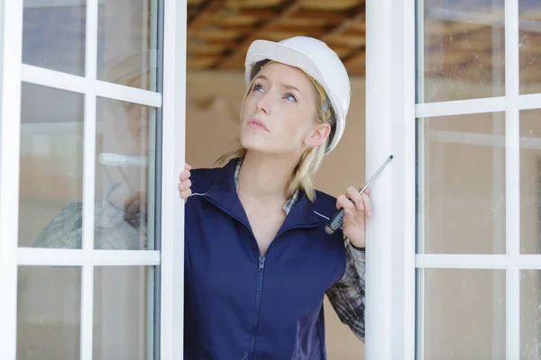 woman with screwdriver installing double glazed windows