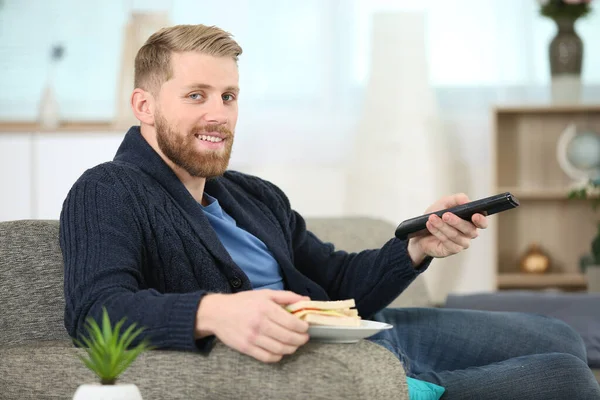 Άνθρωπος Αλλαγή Τηλεοπτικό Κανάλι Τηλεχειριστήριο Ενώ Τρώει Σάντουιτς — Φωτογραφία Αρχείου