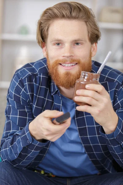 Mężczyzna Jedzący Czekoladę Podczas Oglądania Telewizji — Zdjęcie stockowe