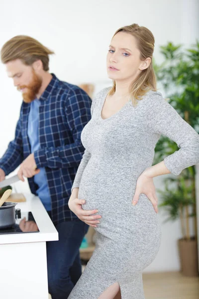 Těhotná Žena Zažívá Bolest Jako Manžel Vaří Jídlo — Stock fotografie