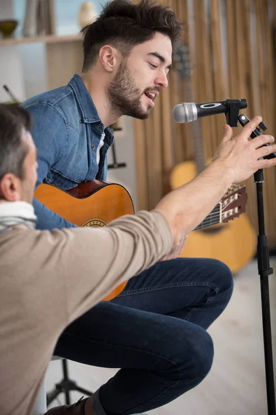 Gitar Çalan Mikrofona Şarkı Söyleyen Genç Adam — Stok fotoğraf