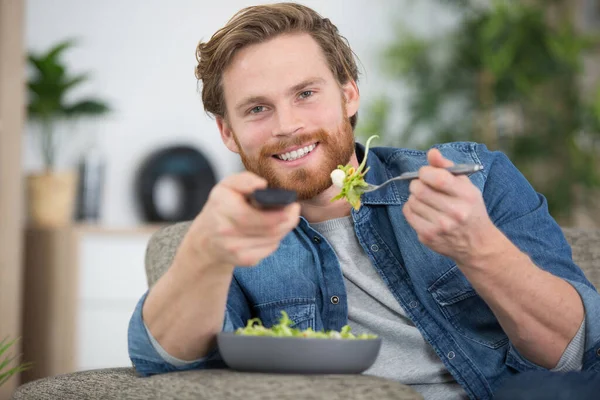 Man Veranderende Kanaal Met Afstandsbediening Tijdens Het Eten Van Salade — Stockfoto