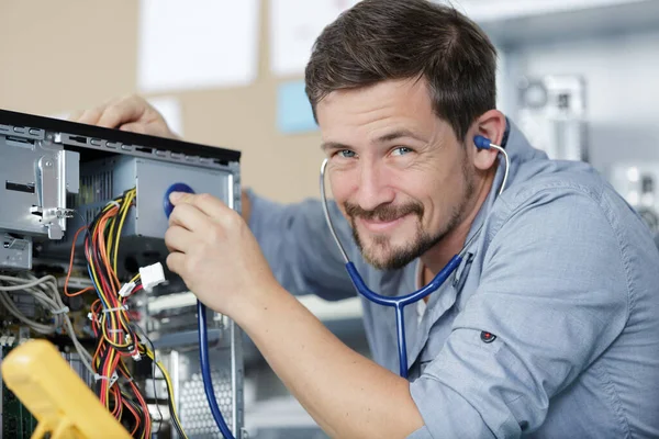 happy professional repairman repairing computer in workshop