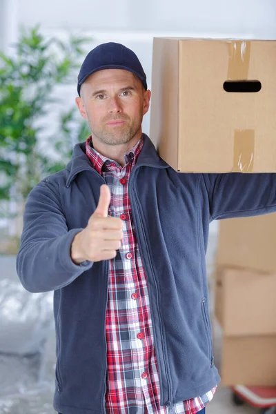smiling delivery man with box showing thumb up