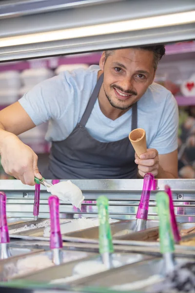 アイスクリームをセレクトするエプロンの若いひげ付き男 — ストック写真