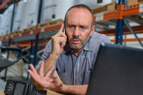 warehouse manager angry while talking on phone