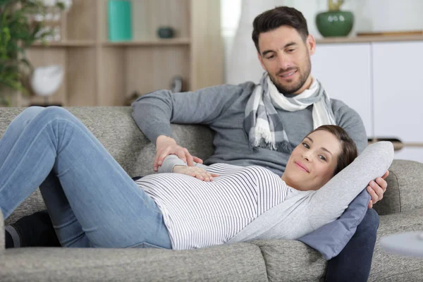 ソファーに横たわっている若い男と妊婦 ストック写真