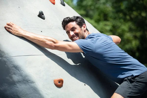 midsection of man climbing wall in gym