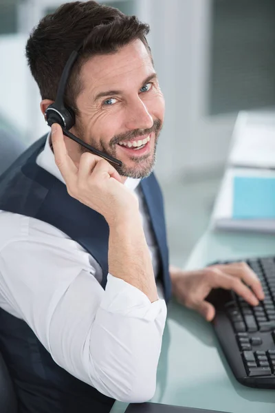 Glimlachende Man Met Een Koptelefoon Typen Het Toetsenbord — Stockfoto