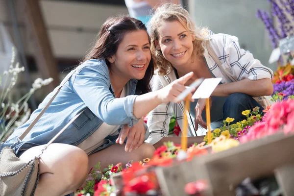 happy female friends shopping for flowers