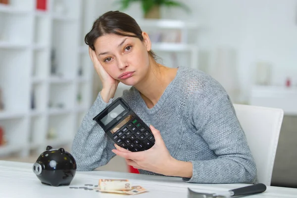 sad woman with calculator and bills on table