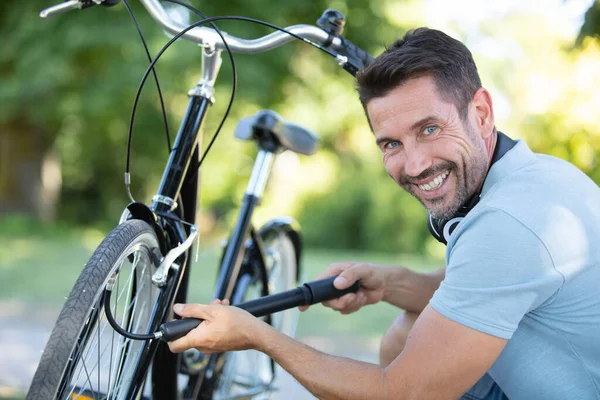 Uśmiechnięty Mężczyzna Napompujący Oponę Roweru — Zdjęcie stockowe
