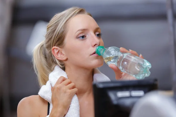 beautiful woman drinking from water bottle after exercising