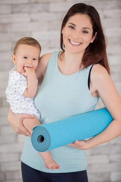 young mom in sports wear holding her little baby