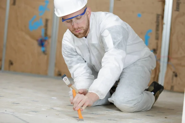 worker with hammer and chisel repairs house floor