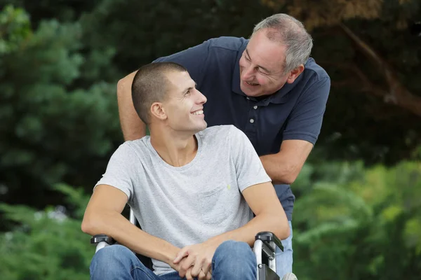 Baba Oğul Parkta Tekerlekli Sandalyesinde Oturuyor — Stok fotoğraf