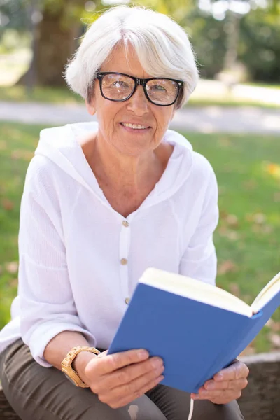 Mujer Jubilada Leyendo Libro Sobre Hierba — Foto de Stock