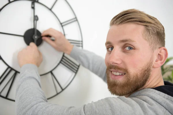man setting the time on an ornate clock