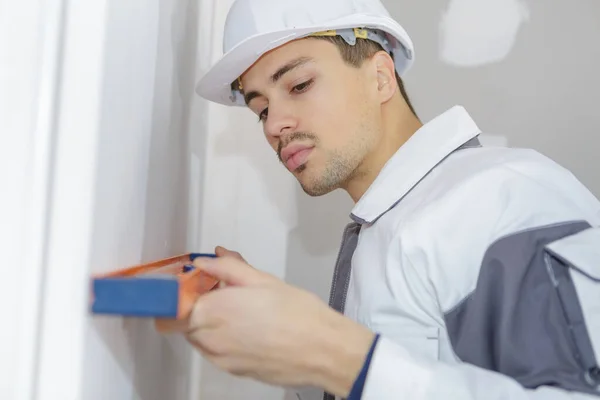 Young Worker Holding Spirit Level Wall — Stock Photo, Image