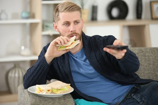 Homme Changer Chaîne Télévision Avec Télécommande Tout Mangeant Sandwich — Photo
