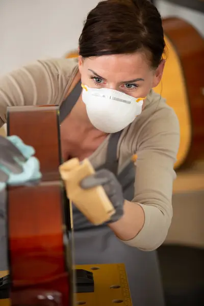 Luthier Feminino Usando Uma Máscara Usando Lixa Uma Guitarra — Fotografia de Stock