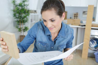 young woman assembling furniture in new apartment clipart