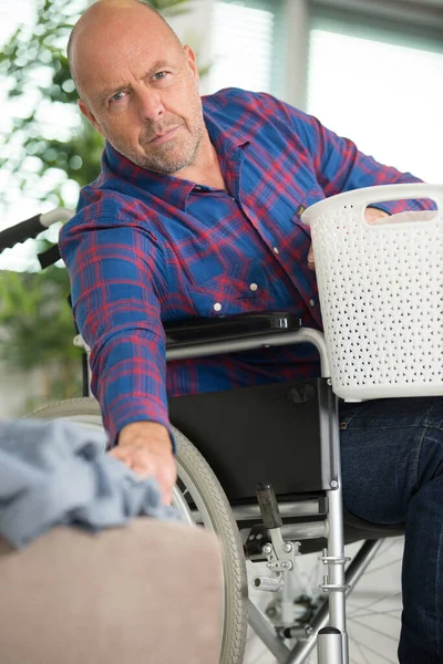服のバスケットを持っている車椅子の男 — ストック写真