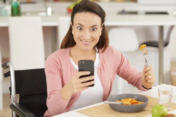 disable woman eating spaghetti using smart phone for selfie