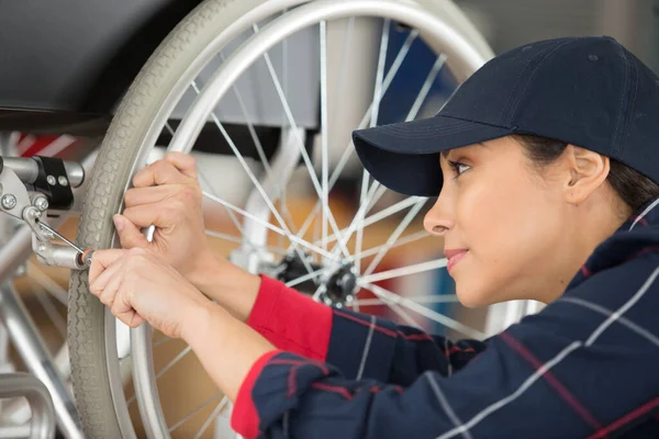 Kobieta Pracownik Regulujący Hamulce Wózku Inwalidzkim — Zdjęcie stockowe