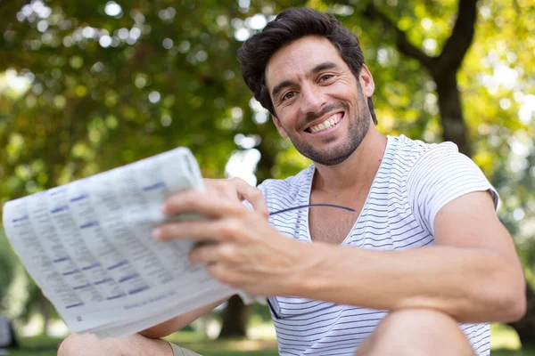 一个英俊的男人在公园里看报纸 — 图库照片