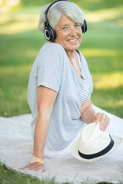 Mature Woman Listening Music While Laying Grass — Fotografia de Stock