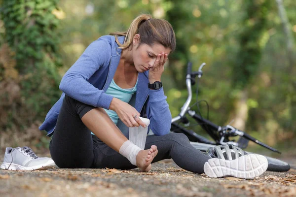 自転車から落ちた後に足首を包む女性 — ストック写真
