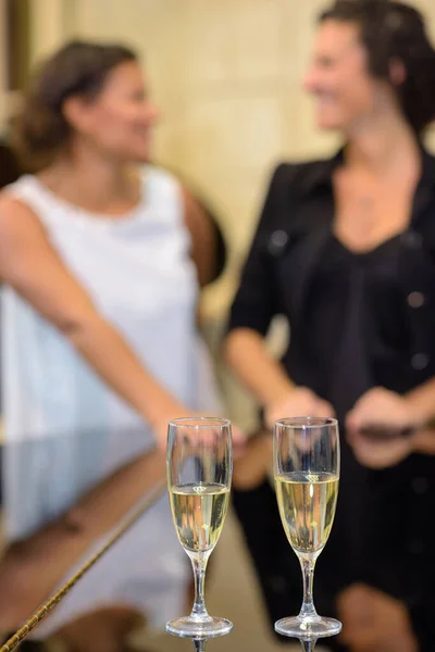 Closeup of champagne flutes, women in background