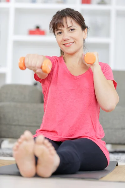woman exercising with dumbbells at home