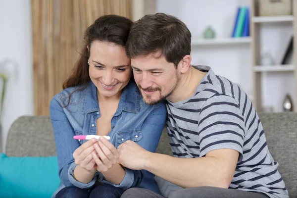 happy couple with pregnancy test at home