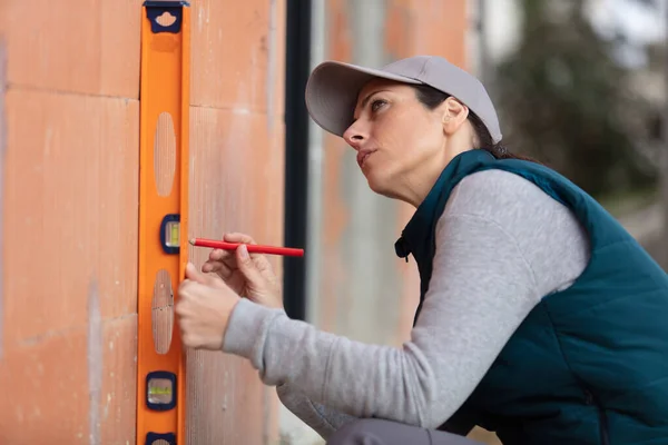 Female Builder Using Spirit Level Exterior Wall — Stock Photo, Image