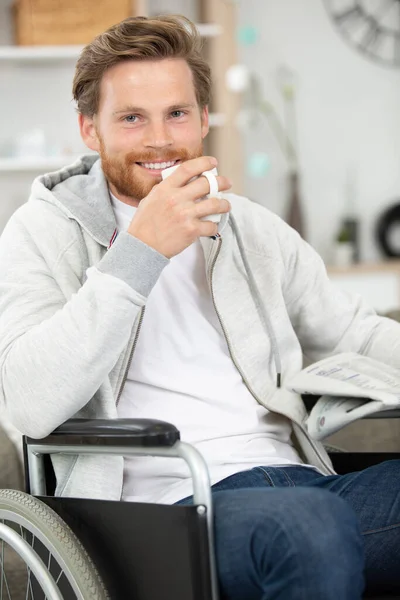 Человек Инвалидном Кресле Держит Газету Горячий Напиток — стоковое фото