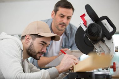 supervisor assessing apprentice using circular saw clipart