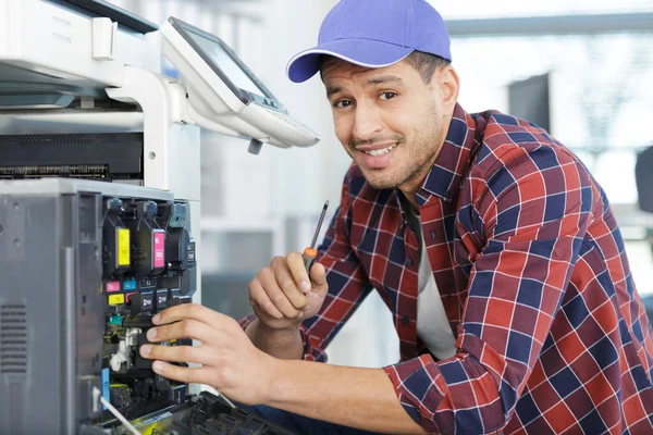 maintenance man with screwdriver checks photocopier ink
