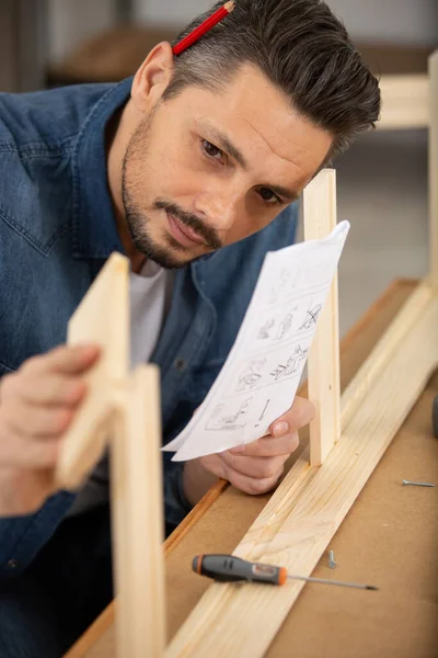 Man Assembles Wooden Furniture Instructions — Stock Photo, Image