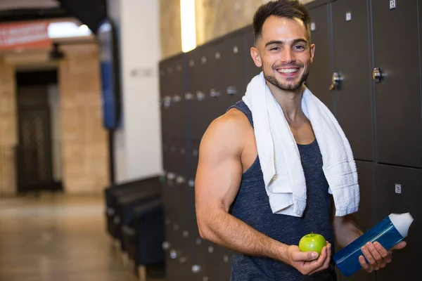 smiling young man in locker room of the gym