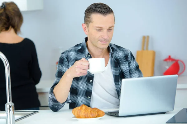 Mann Frühstückt Mit Blick Auf Laptop — Stockfoto