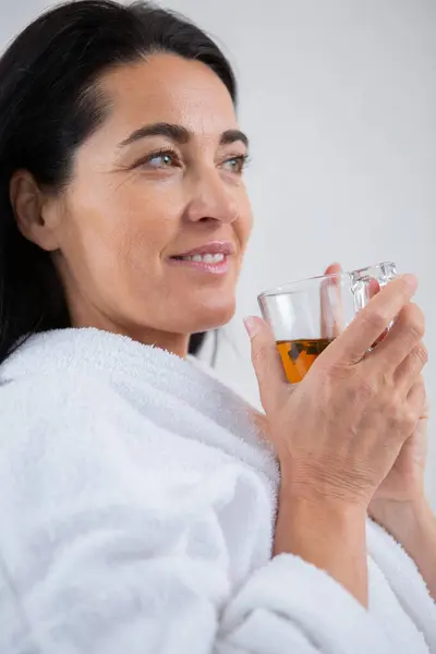 pretty woman in a bathrobe enjoying a cup tea