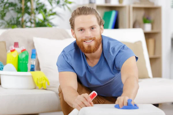 enthusiastic man cleaning a sofa