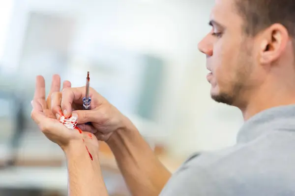man holding screwdriver and tending bleeding hand