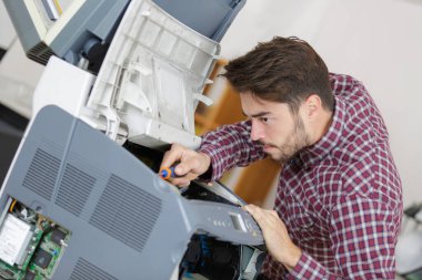 male technician working on electrical appliance with screwdriver clipart